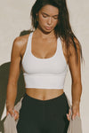 Front view of model posing in the fitted stretchy cropped white flexrib Varsity Tank Bra with a scoop neckline