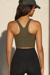 Back view of model posing in the fitted stretchy cropped woodland flexrib Varsity Tank Bra with a racerback silhouette