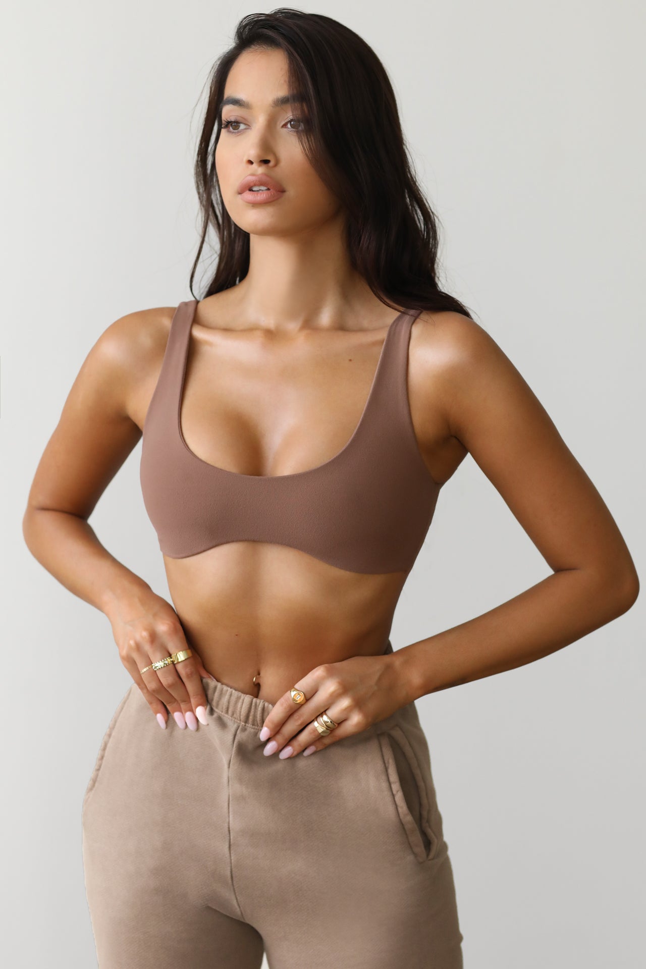 Front view of model posing in the stretchy and sculpting sueded mocha contour bra with a deep scoop neckline and curved hem