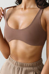 Close up detail front view of model posing in the stretchy and sculpting sueded mocha contour bra with a deep scoop neckline and curved hem