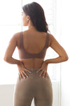 Back view of model posing in the stretchy and sculpting sueded mocha contour bra with a scoop back and curved hem