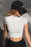Front view of model posing in the fitted cropped pearl grey rib Contrast Stitch Crop Tee with stitched seaming, cap sleeves and a mini mock neckline