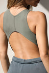 Close up back view of model posing in the fitted cropped summit flexrib Curve Crop Tank with a vertical stitch detail down the back, a curved hemline in an inverted u-shape and mini v back