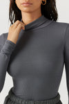 Close up front view of model posing in the form fitting stretchy smoke rib Classic Turtleneck long sleeve top