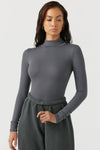 Front view of model posing in the form fitting stretchy smoke rib Classic Turtleneck long sleeve top