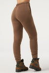 Back view of model from the waist down posing in the tapered cocoa french terry Empire Jogger with side pockets and an elastic waistband and ankle cuffs