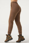 Side view of model from the waist down posing in the tapered cocoa french terry Empire Jogger with side pockets and an elastic waistband and ankle cuffs