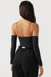 Back view of model posing in the form fitting sueded onyx Off The Shoulder Long Sleeve Top in a cold shoulder design with ultra thin corded straps, attached sleeves and a straight neckline