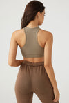 Back view of model posing in the fitted stretchy taupe flexrib Stitch Bra top with a racerback and stitch detaiiling