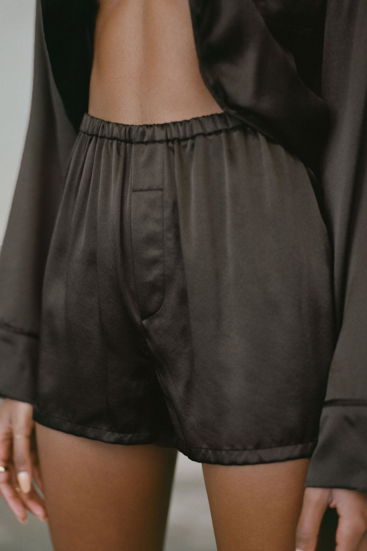 Close up front view of model from the waist down posing in the comfortable, boxer-style espresso Relaxed Silk Short with an elastic waistband