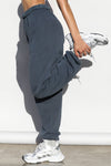 Side view of model from the waist down wearing the oversized loose fit washed navy french terry Oversized Jogger with an elastic waistband and ankle cuffs