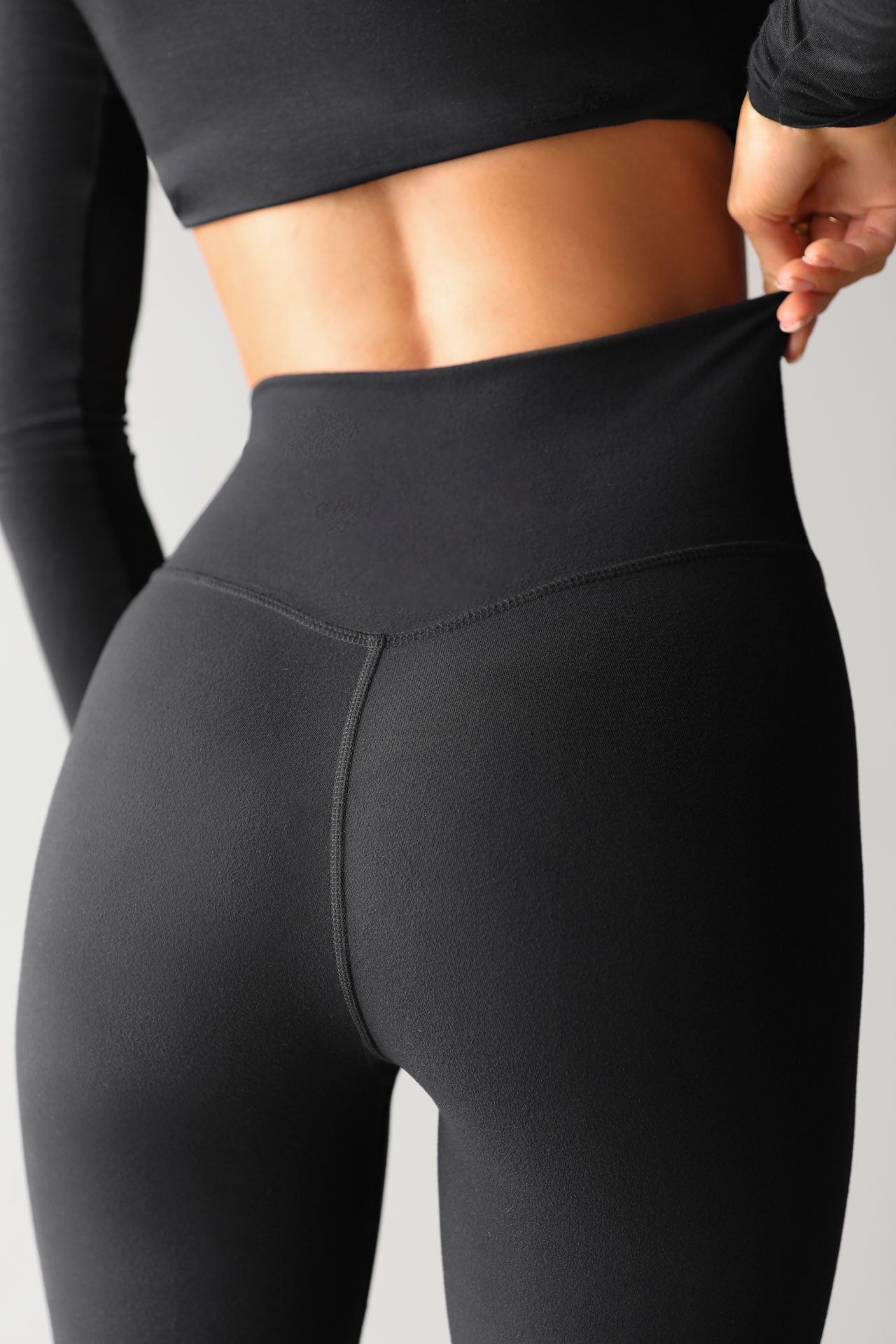 Close up detail back view of model from the waist down posing the full length and high-waisted sueded onyx Second Skin Legging with a wide, v-shaped waistband