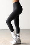 Side view of model from the waist down posing the full length and high-waisted sueded onyx Second Skin Legging with a wide, v-shaped waistband