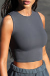 Close up detail side view of model posing in the fitted and cropped contouring sueded navy Second Skin Tank with a high crew neckline
