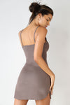Back view of model posing in the form fitting stretchy mauve rib mini Slip Dress with thin straps, a u neckline and a tiny side slit at the hem