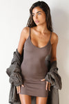 Front view of model posing in the form fitting stretchy mauve rib mini Slip Dress with thin straps, a u neckline and a tiny side slit at the hem