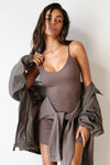 Front view of model posing in the form fitting stretchy mauve rib mini Slip Dress with thin straps, a u neckline and a tiny side slit at the hem