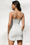 Back view of model posing in the form fitting stretchy pearl grey rib mini Slip Dress with thin straps, a u neckline and a tiny side slit at the hem