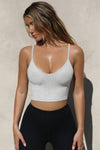 Front view of model posing in the fitted and stretchy pearl grey flexrib Strappy Crop Tank with thin straps and a scooped u neckline