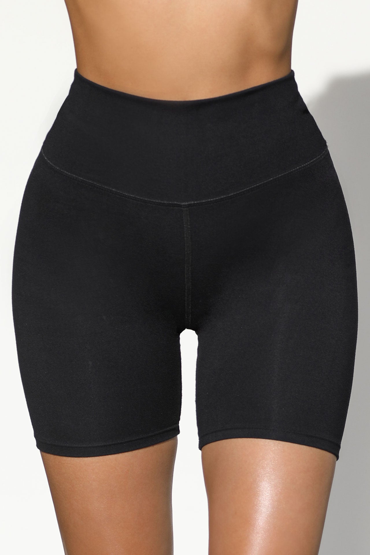 Close up front view of model from the waist down wearing the soft stretchy high-waisted sueded onyx Biker Short with a wide waistband