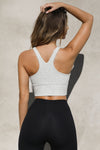 Back view of model posing in the fitted stretchy cropped pearl grey flexrib Varsity Tank Bra with a racerback silhouette