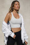 Front view of model posing in the fitted stretchy cropped pearl grey flexrib Varsity Tank Bra with a scoop neckline